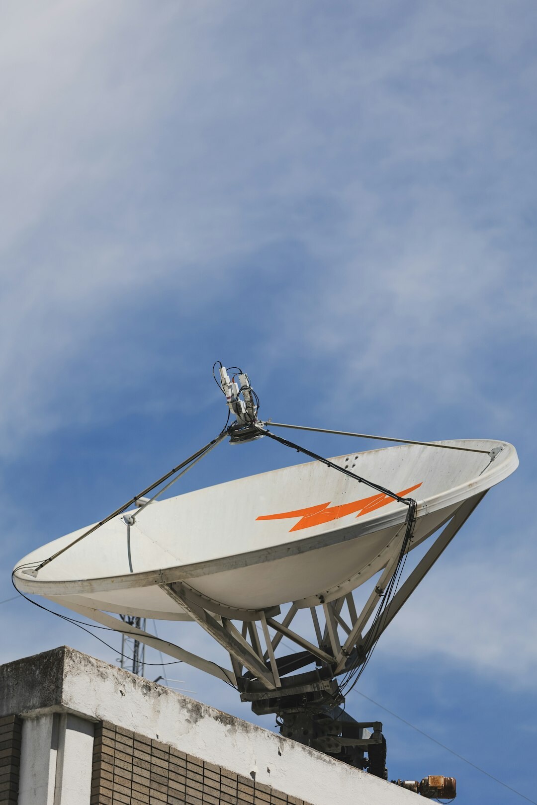 Satellite uplink dish against a cloudy sky for content distribution